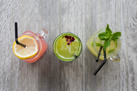 Natural fruit drinks in masonry jars on wooden surface
