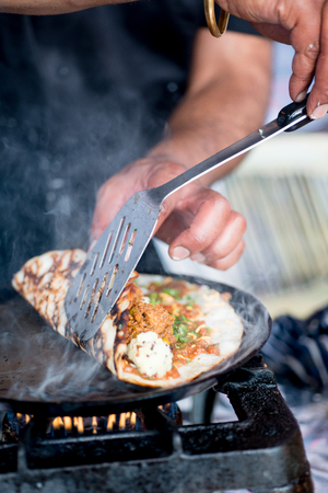 Indian dosa being rolled with a spatula on a hot skilletの写真素材