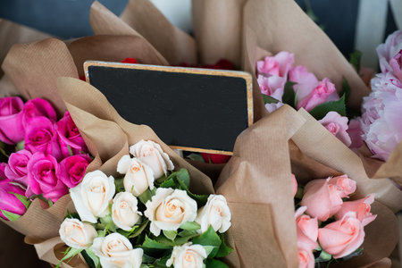 A blank sign in the middle of wrapped bouquets of sorted color roses
