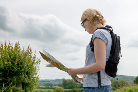 Lady hiker holding and reading a map in the sunny outdoors