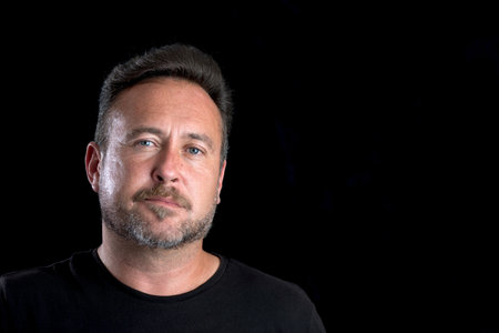 Bearded adult white male's face over a black background with copy space