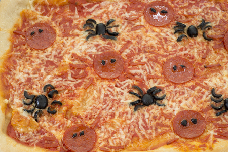 Closeup of halloween pizza with spider-shaped pepperoni and olivesの写真素材