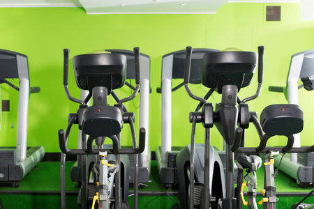 Treadmills and elliptical machines in a green walled gym