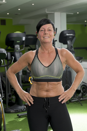 Muscular lady in a crop top stands and poses in a gymのeditorial素材