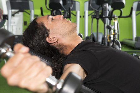 Closeup of long-haired guy performing flat bench chest flyesのeditorial素材