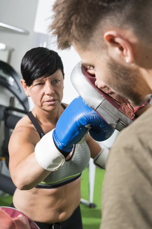 Athletic lady wearing boxing gloves throws a punch at a mittenのeditorial素材