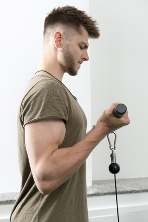 Young man performing bicep curl with cable machineのeditorial素材