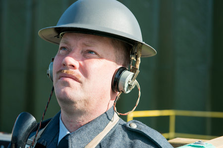 Man in British World War II gear using a vintage radio communications equipment