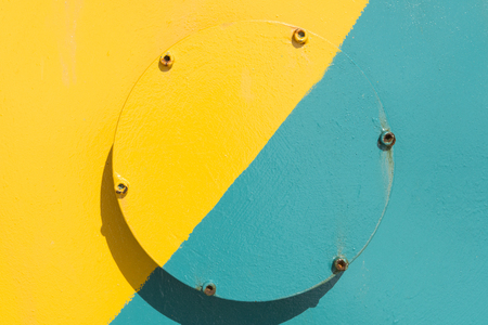 Round industrial cast iron plug painted in yellow and teal for backgroundsの写真素材