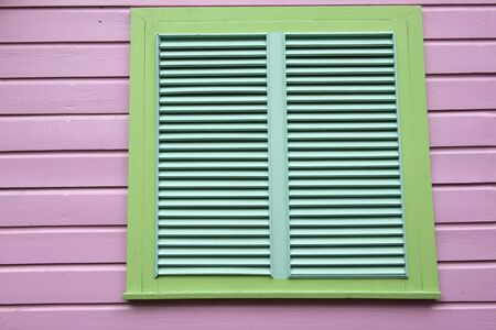 Green louvered window on a pink wooden panel wallの写真素材