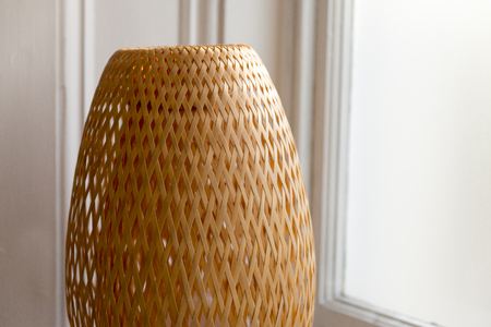 Wicker woven lampshade beside a windowの写真素材