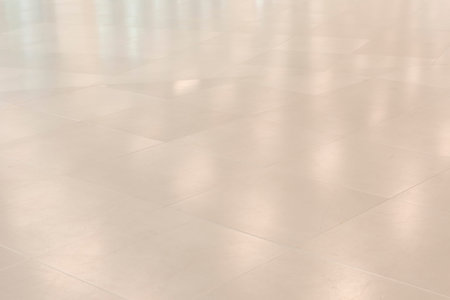 Shiny white tiled floor with reflection of ceiling lights for backgrounds