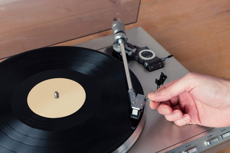 Hand placing the stylus of a record player onto a spinning vinyl record