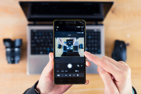 Smartphone in hand and laptop in the background droste effect
