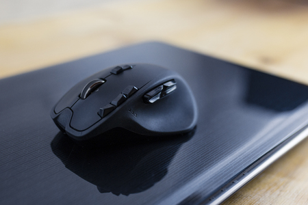 Black gaming mouse on a closed laptop computerの写真素材