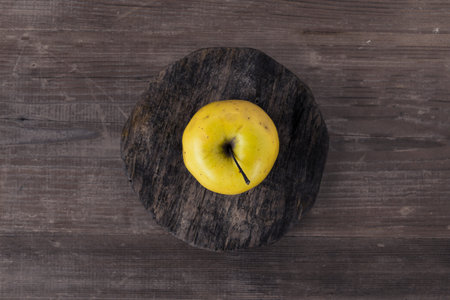 Overhead view of a yellow pear on a round wooden board