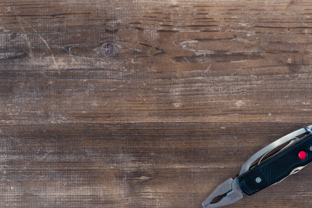 Pocket folding multi-tool on a wooden surface with copy space