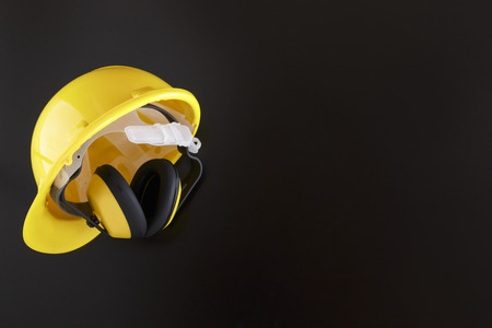 Earmuffs and yellow hard hat on a black background with copy spaceの写真素材