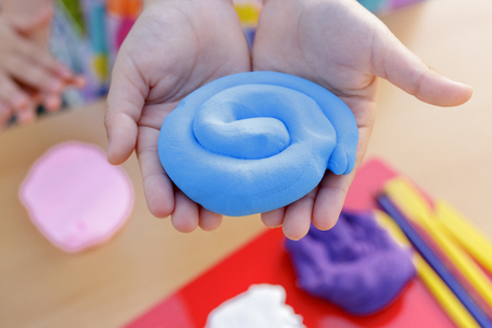 Hands holding a lump of blue modeling soft clayの写真素材