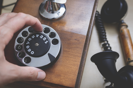 Hand dialing on an antique wooden rotary telephoneの写真素材