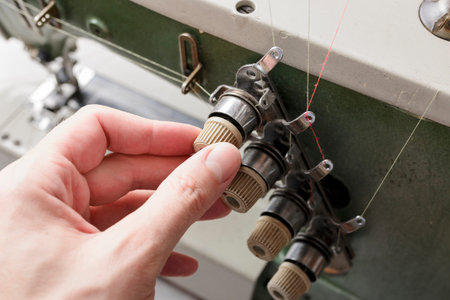 Hand turning a knob on an electric sewing machine