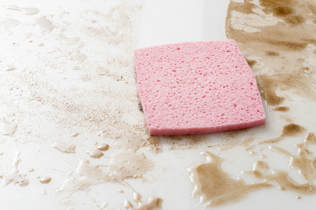 Pink sponge on a counter top or floow covered with spillsの写真素材