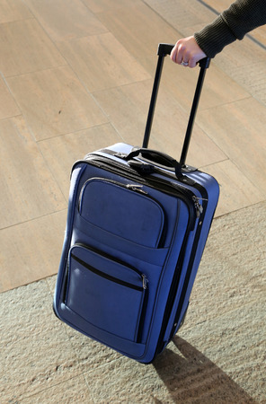 Blue suitcase held by a woman's hand.の写真素材