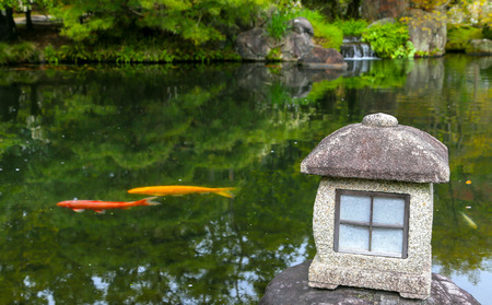 Red and yellow carp fish in a Zen pond in Japan with lantern.の写真素材