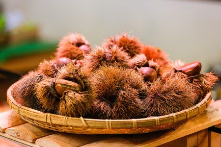 Chestnuts in a bamboo bowl on wooden tableの写真素材