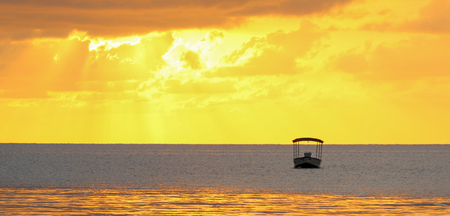 Golden ocean sunset with a boat silhouette.の写真素材