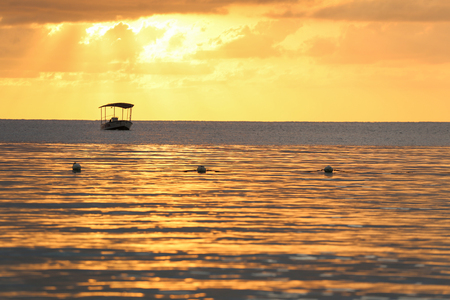 Golden ocean sunset with a boat silhouette.の写真素材