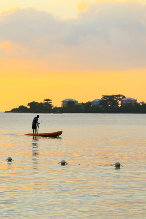 Man silhouette rowing standng on a boat at sunset time.の写真素材