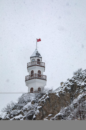 Snowfall in the mountains with a tower and a flag on top