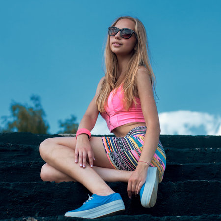 beautiful girl hipster posing on the steps against the sky with cloudsの写真素材