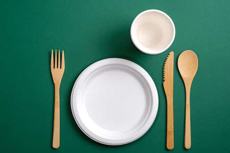 Eco friendly bamboo kitchenware with paper mug and plate on green background. Zero waste, plastic free concept. Sustainable lifestyle. Flat lay, top view.の写真素材