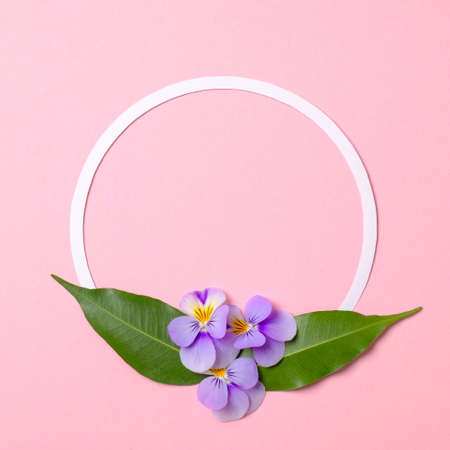 Round floral frame border made of paper circle, flowers petals, green leaves on watercolor spring background. Invitation, greeting card or an element for your design. Top view, abstract art.の写真素材