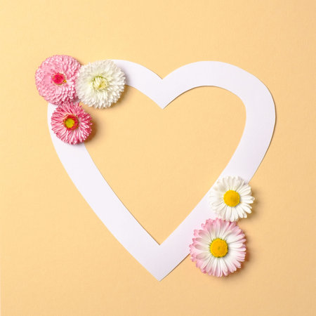 Love nature concept. Daisy flowers and white heart-shaped paper card on pastel yellow background....
