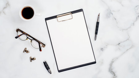 Set of office supplies on white marble table. Home office desk with clipboard, glasses, pen, cup of...
