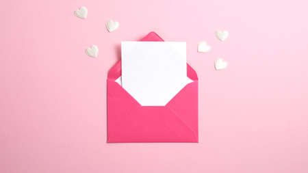 Envelope with blank white paper note inside and Valentine hearts on pink background. Romantic love letter for Valentine's or Mother's day concept.の写真素材