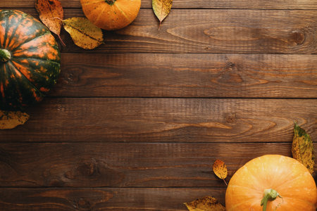 Autumn frame made of pumpkins, dried fall leaves, apples, red berries, walnuts on wooden table....