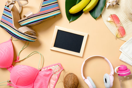 Frame made of summer beach accessories on the yellow background - swimwear, sandals, headphones,...
