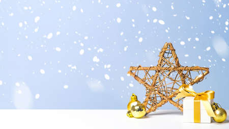 Small Christmas gift box with golden balls and Xmas star in snow on blue background. Christmas, New Year, winter holidays conceptの写真素材