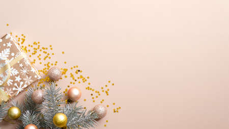 Christmas banner. Ivory Xmas background with fir tree branches, balls and gift box wrapped festive paper. Christmas frame, New Year greeting card template. Flat lay, top view, copy spaceの写真素材