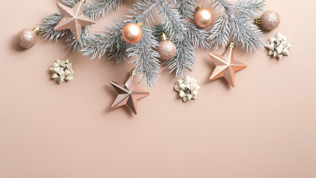 Christmas tree branch with luxury cream color decorations on copper background. Flat lay, top view,...