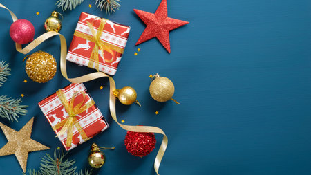 Christmas ornaments on blue background with copy space. Flat lay gift boxes, pine tree branch,...