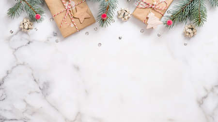 Christmas or New Year banner. Xmas greeting card. Christmas gifts and fir tree branches on white marble background. Flat lay, top view, overheadの写真素材