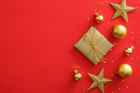 Top view golden Christmas decorations on red background. Flat lay gift box, stars, balls, glittering...
