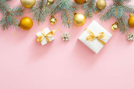 Christmas frame border with fir tree branches, Christmas golden balls, presents on pastel pink background. Flat lay, top view.の写真素材