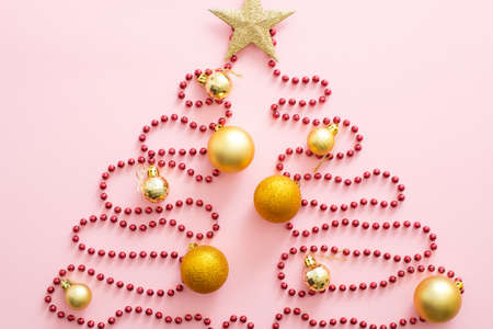 Christmas tree made of red garland, golden bauble and star. Flat lay, top view, overhead. Xmas creative layout. Christmas, winter holiday, New Year concept.の写真素材