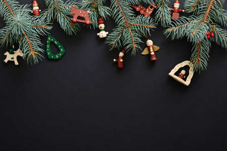 Black Christmas background with handmade wooden decorations and fir tree branches. Christmas holiday celebration, winter, New Year concept. Christmas banner mockup, greeting card template.の写真素材